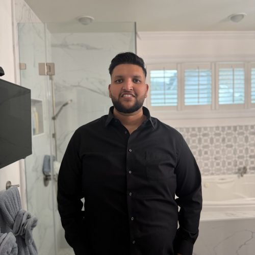 Raj Singh of RS Dynamic Builders standing inside a completed bathroom remodel.